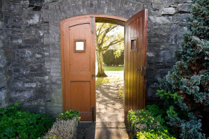 Wooden doors ajar in a stone garden wall.