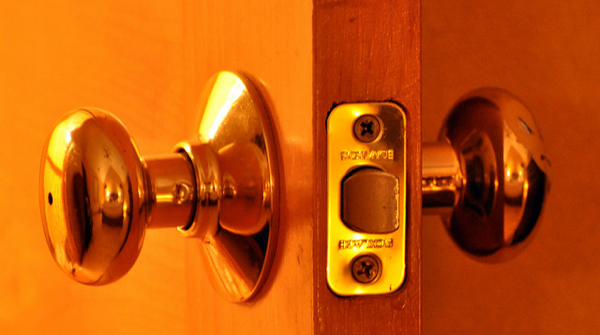 Close up of an open door in golden light, where one can see the lock and both knobs.