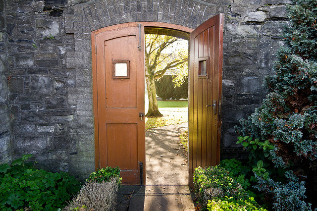 Wooden doors ajar in a stone garden wall.